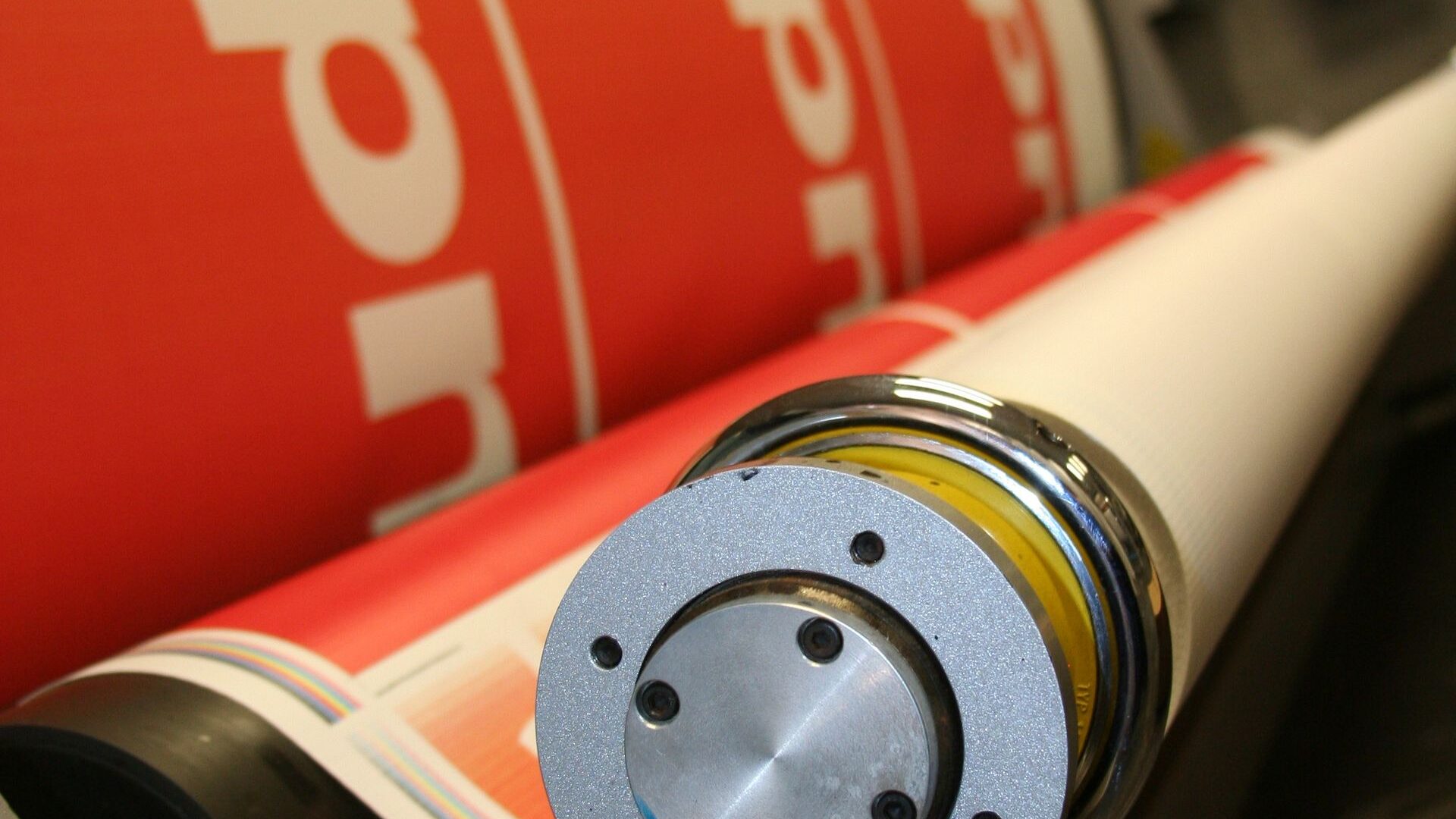 Close-up of printing rollers with red printed sheet