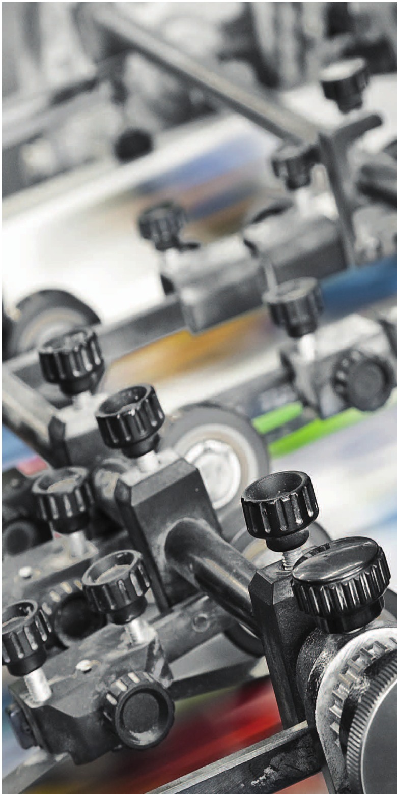 Close-up of offset printing press controls and rollers